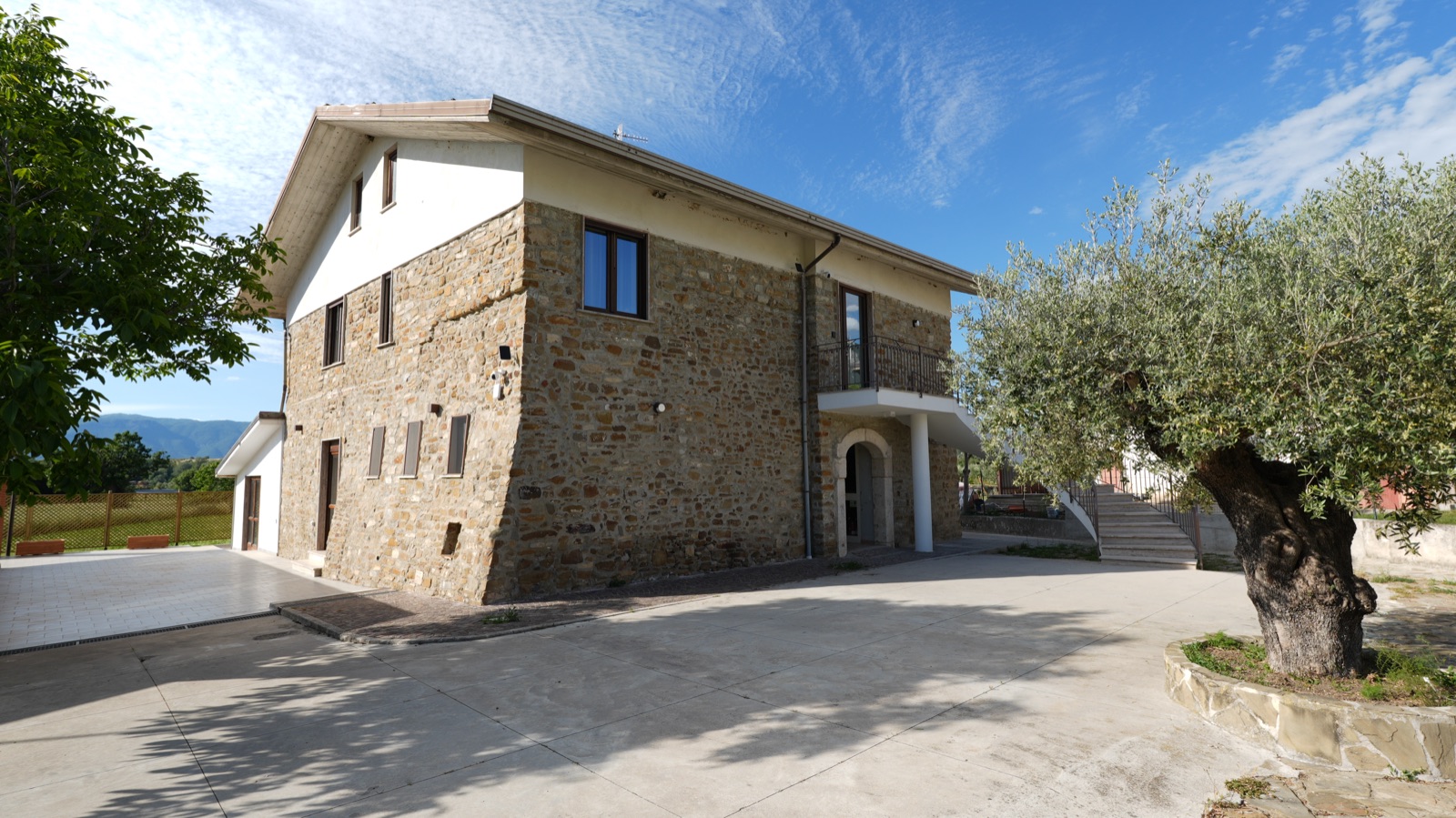 Ingresso ad arco del casale in pietra con parcheggio